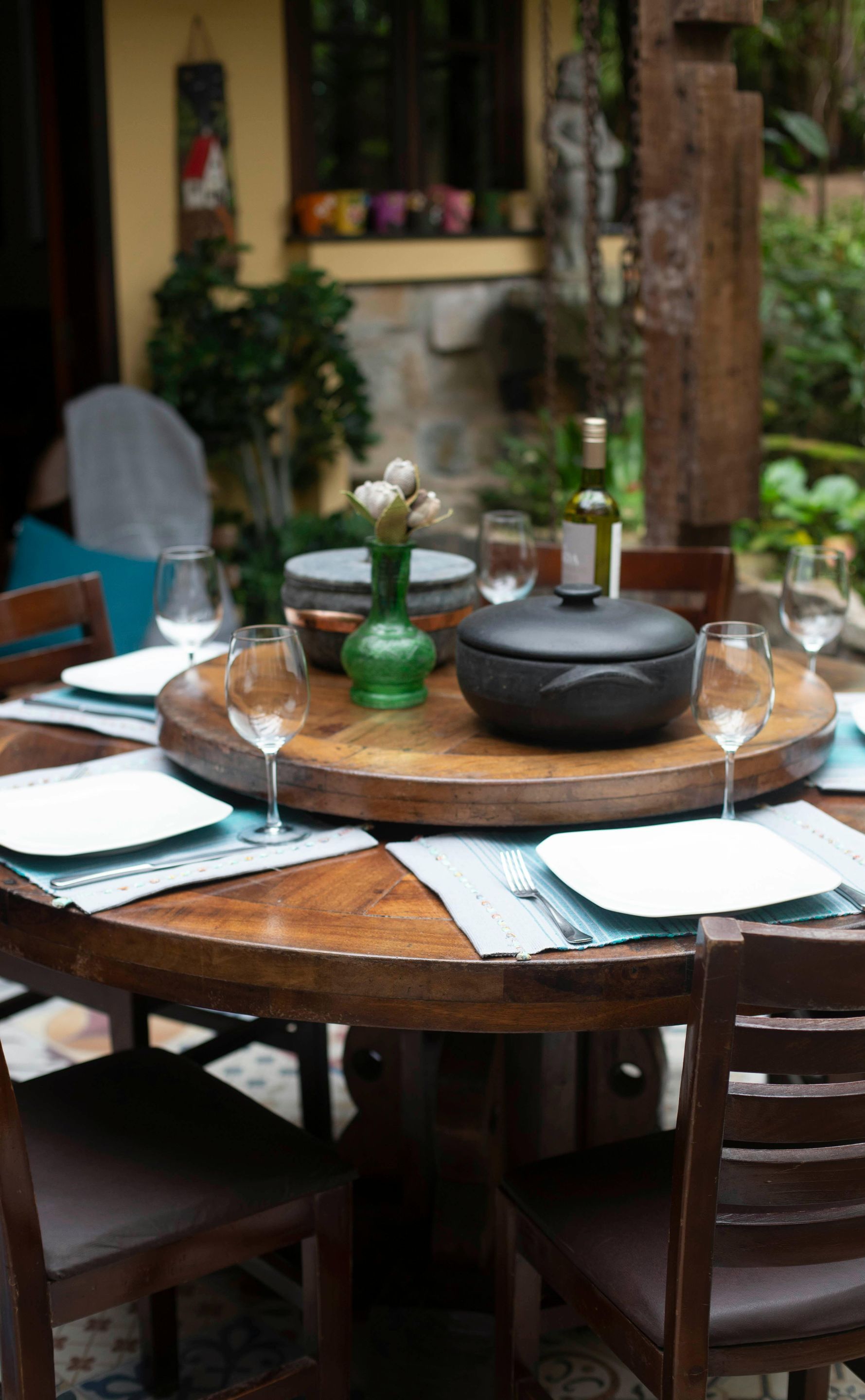 A wooden table with plates , wine glasses and a pot on it.