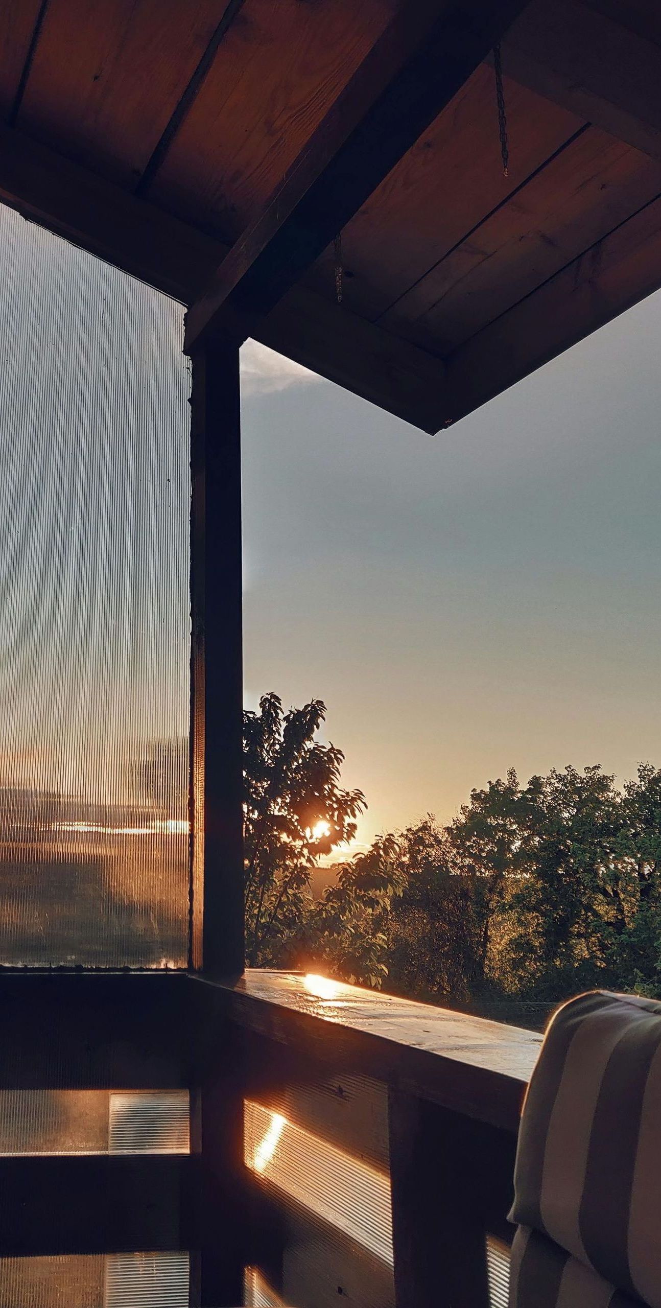 A balcony with a view of a sunset over a forest.