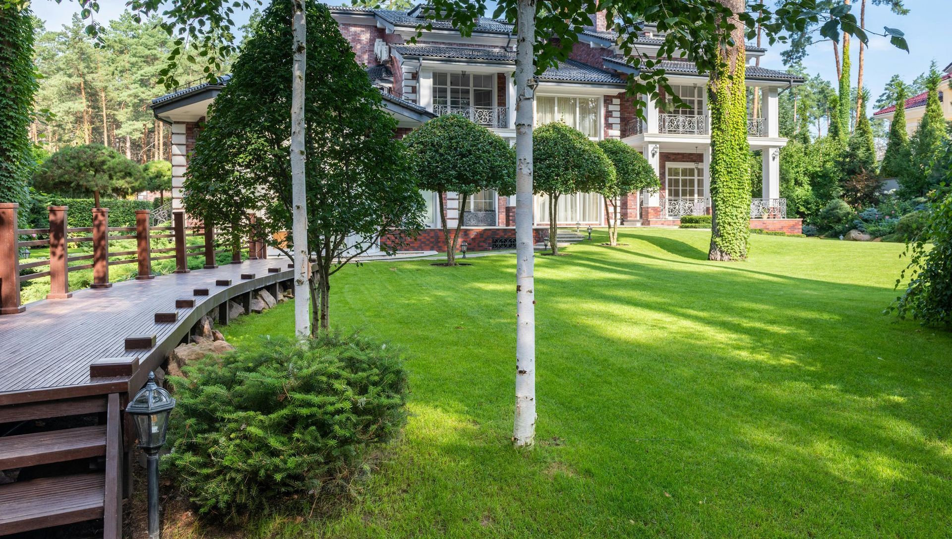 A large house with a lush green lawn and trees in front of it.