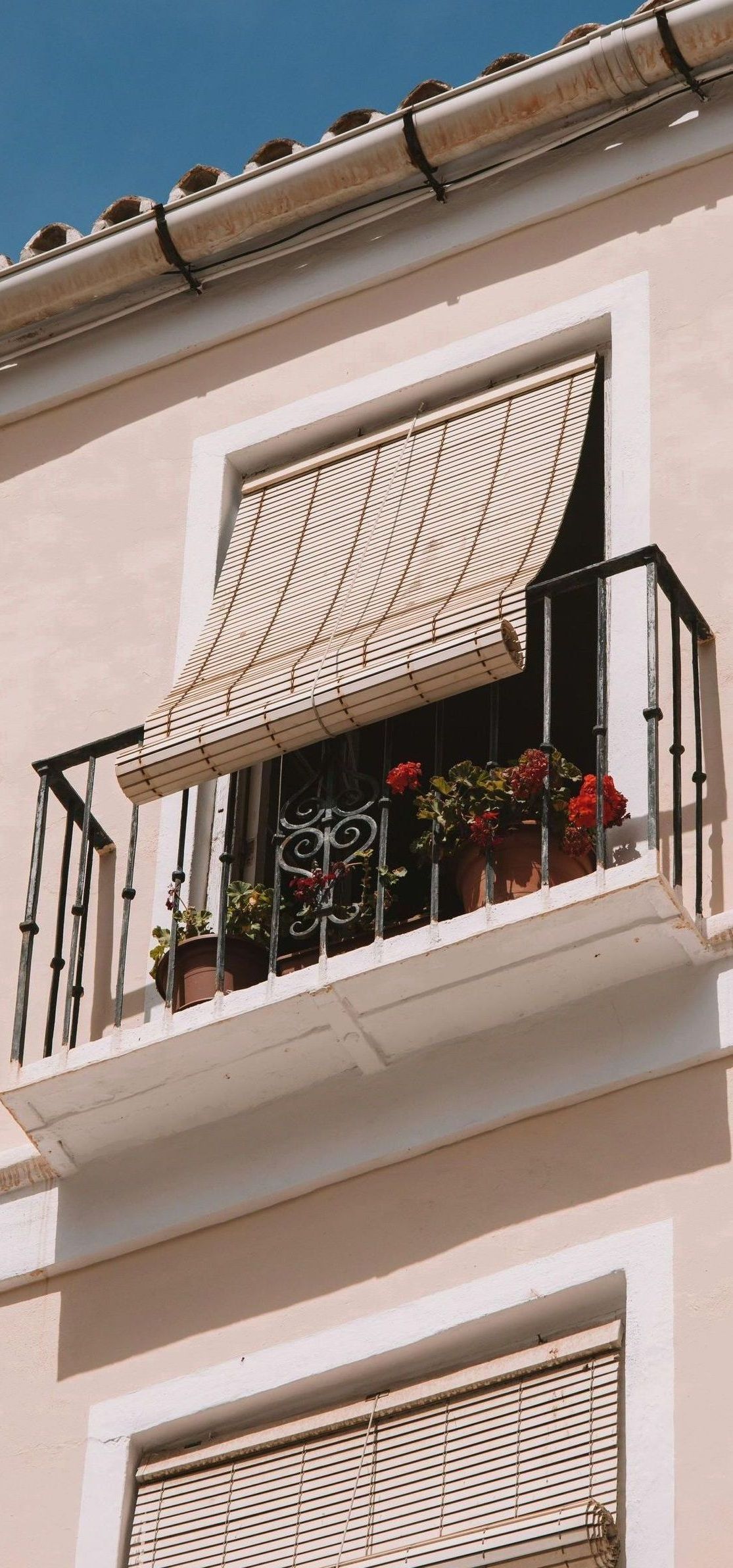 A white house with a blue awning on the balcony.