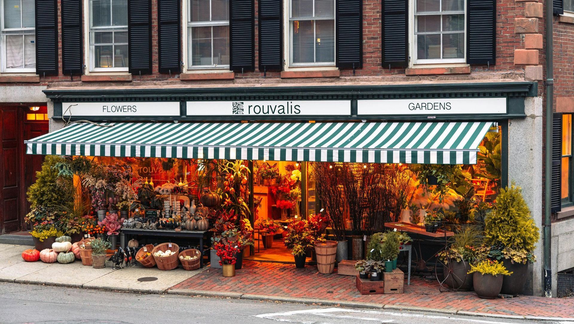 A flower shop with a striped awning on the front of it.