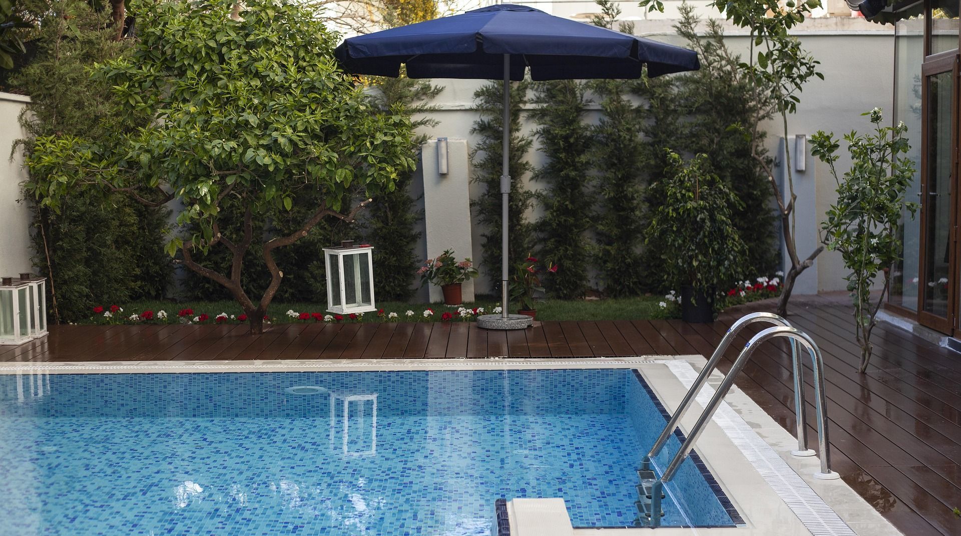 A large swimming pool with a blue umbrella in the background