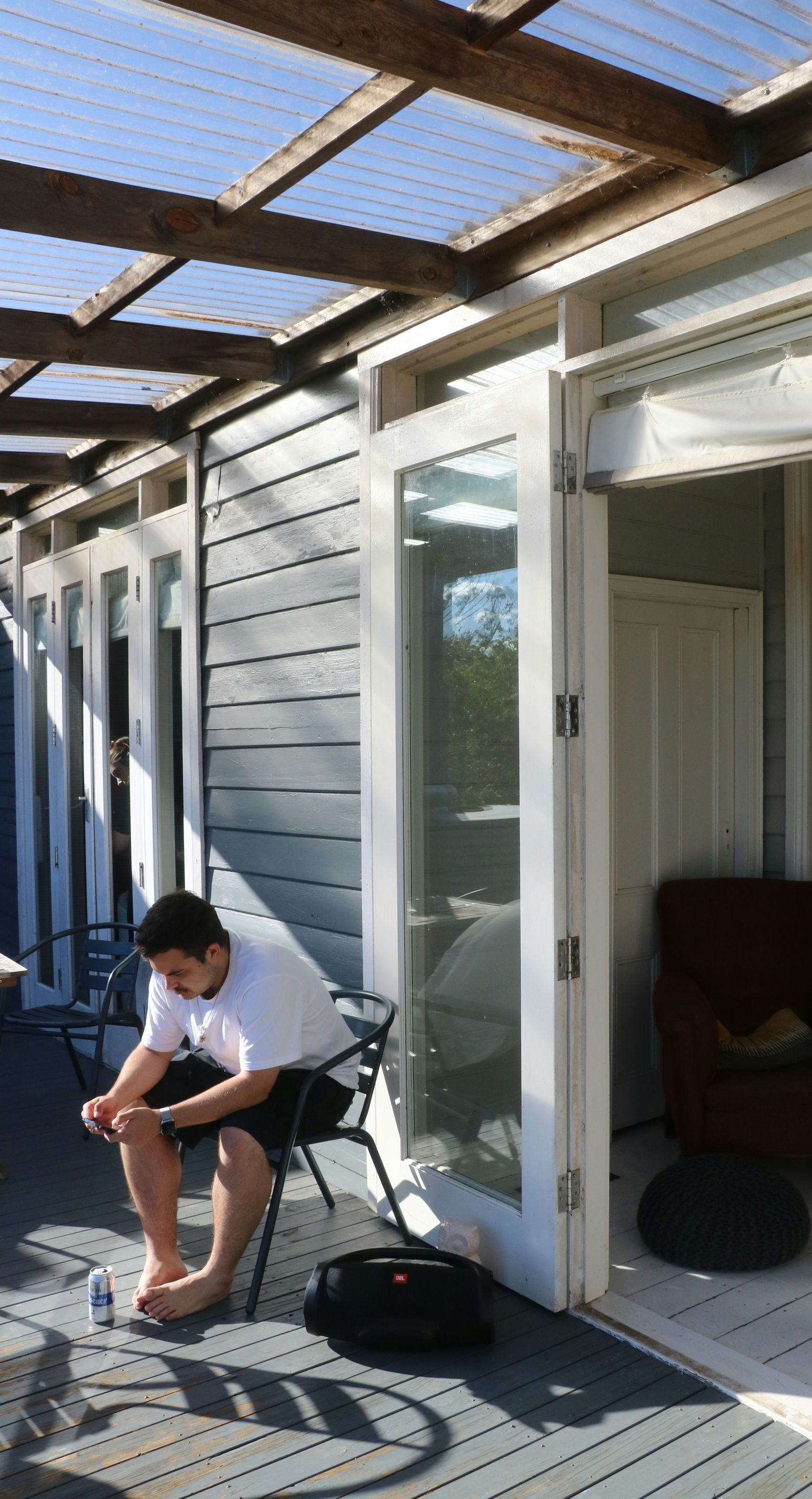 A man is sitting on a chair outside of a house.