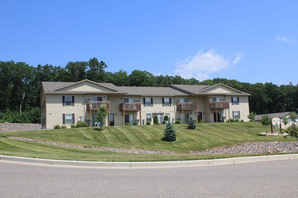 A large apartment building with a lush green lawn in front of it.