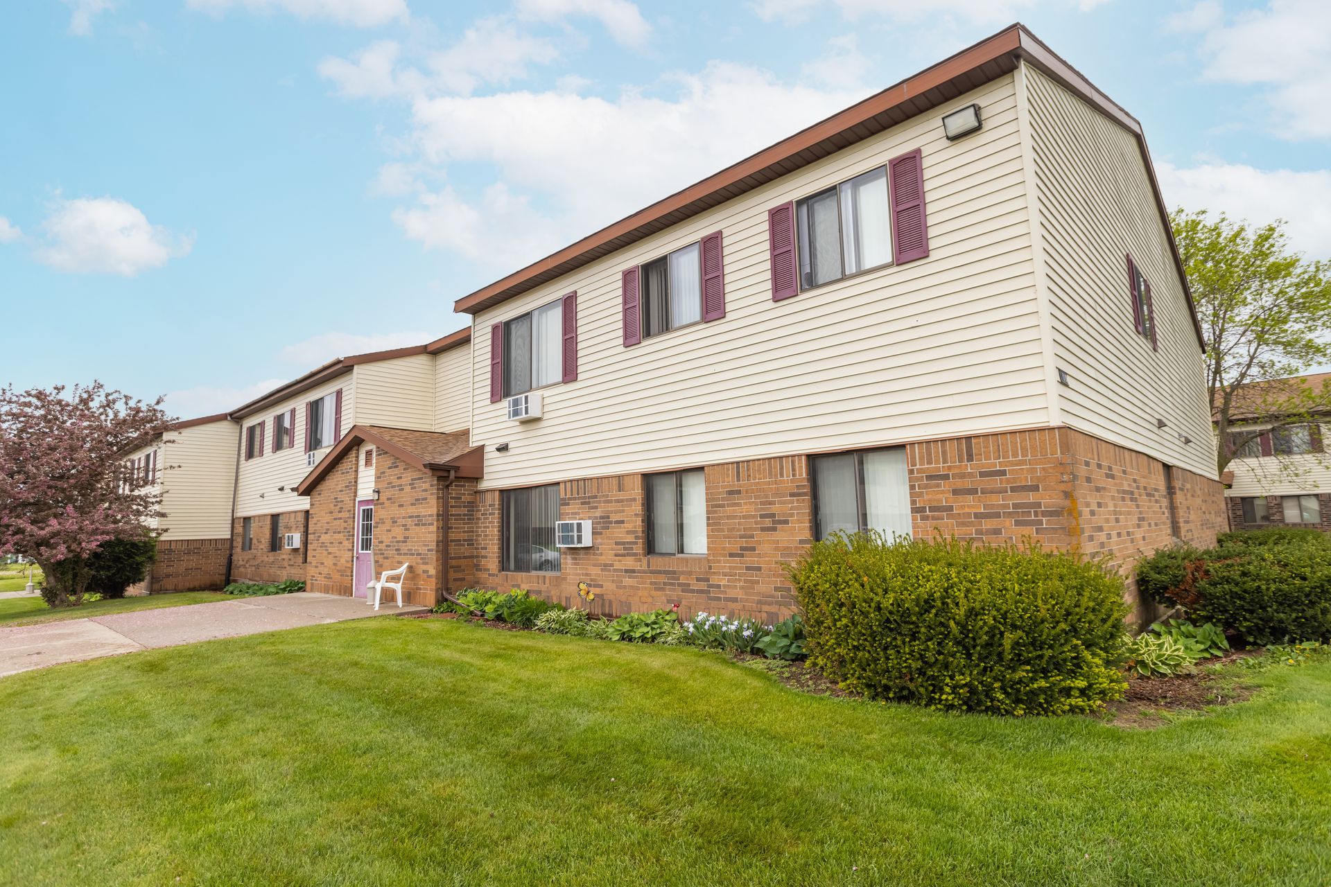 A large apartment building with a lot of windows and a lush green lawn in front of it.