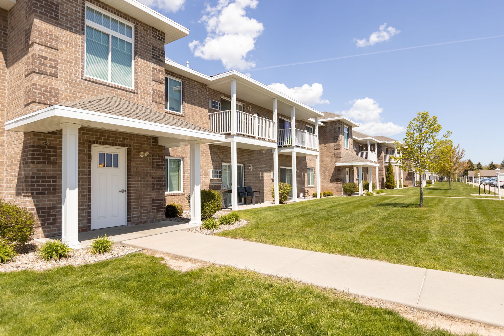 A row of apartment buildings with a sidewalk in front of them.