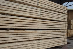 Una pila di travi di legno posizionate una sopra l'altra in un magazzino.
