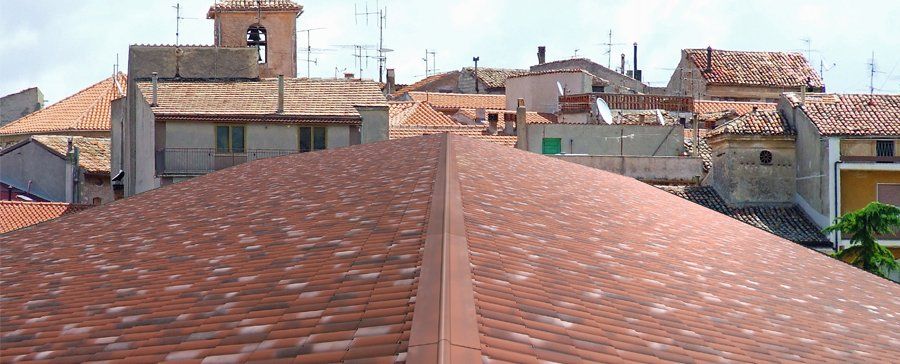 Una fila di edifici con un tetto di tegole rosse e un campanile sullo sfondo.