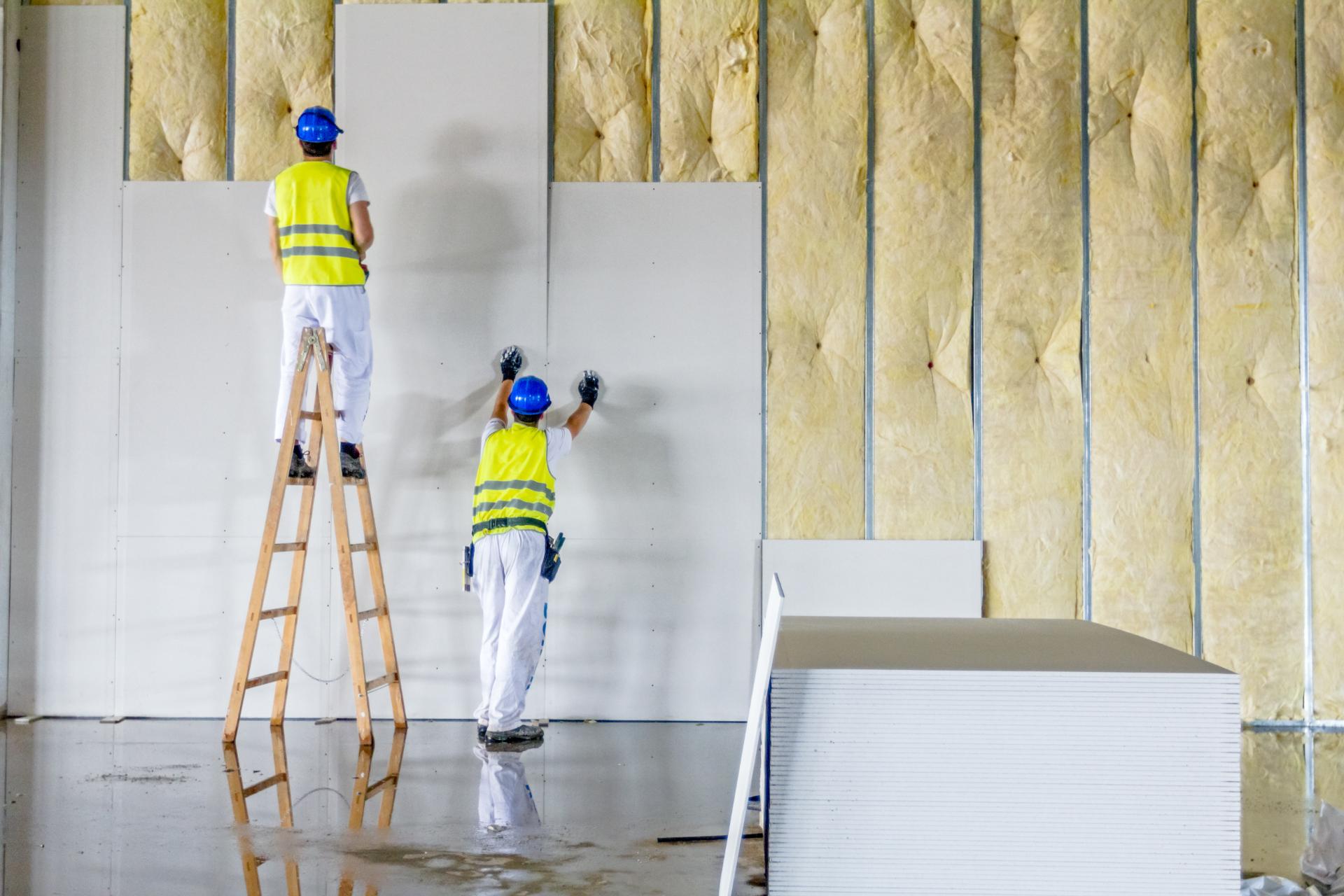 Due operai edili stanno installando l'isolamento su un muro.