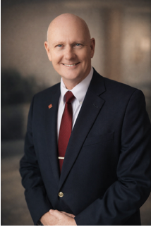 Person handing keys to another person over a signed document on a wooden table, likely a real estate closing.