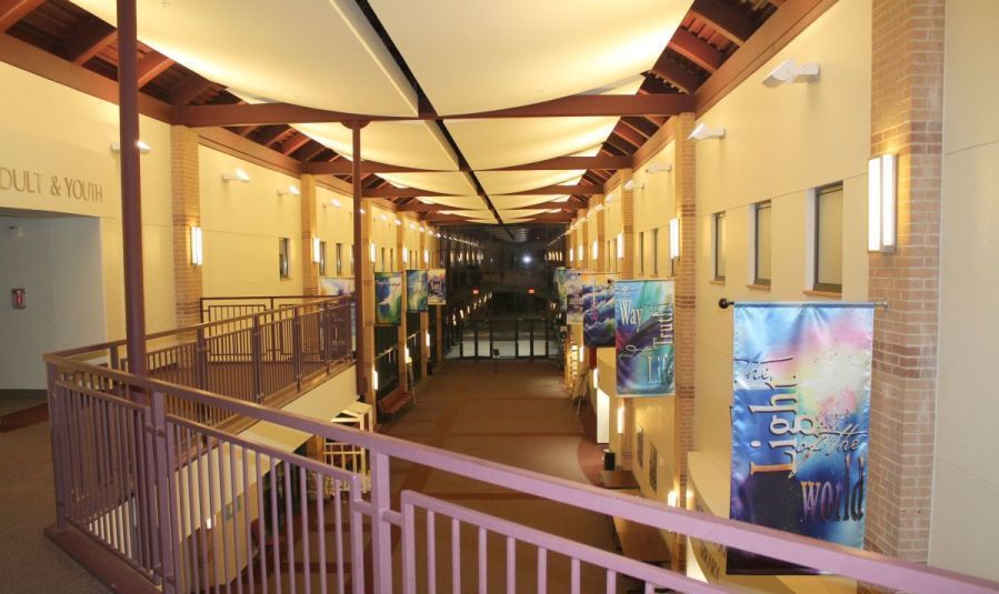 A long hallway with a purple railing and a sign that says light of the world