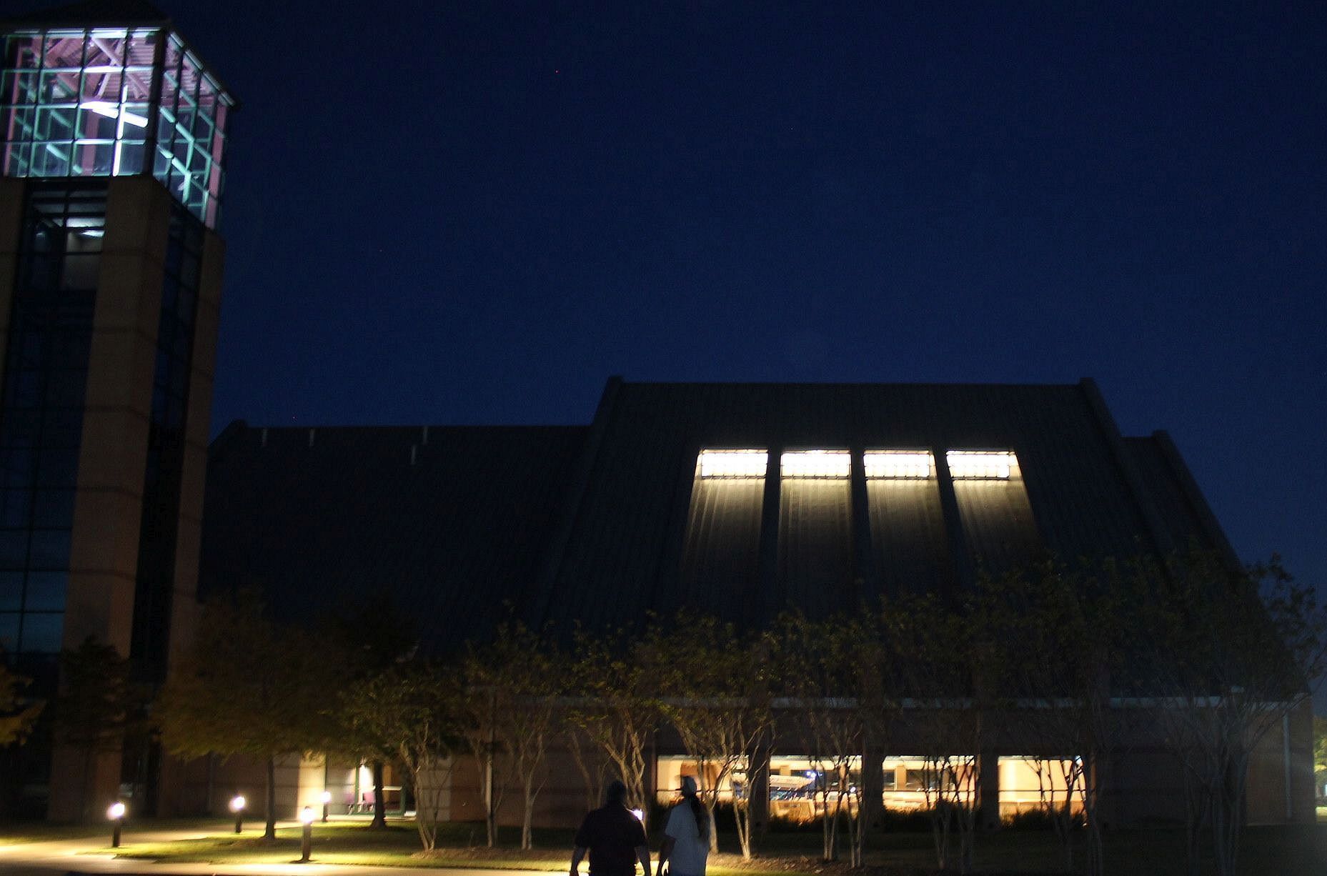 A couple walking in front of a building at night