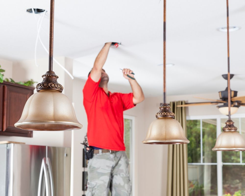 Close-up of a young contractor from MHSC Energy installing a lamp in a living room in College Statio