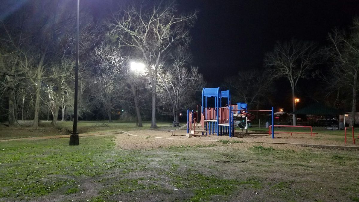 A playground is lit up at night in a park.