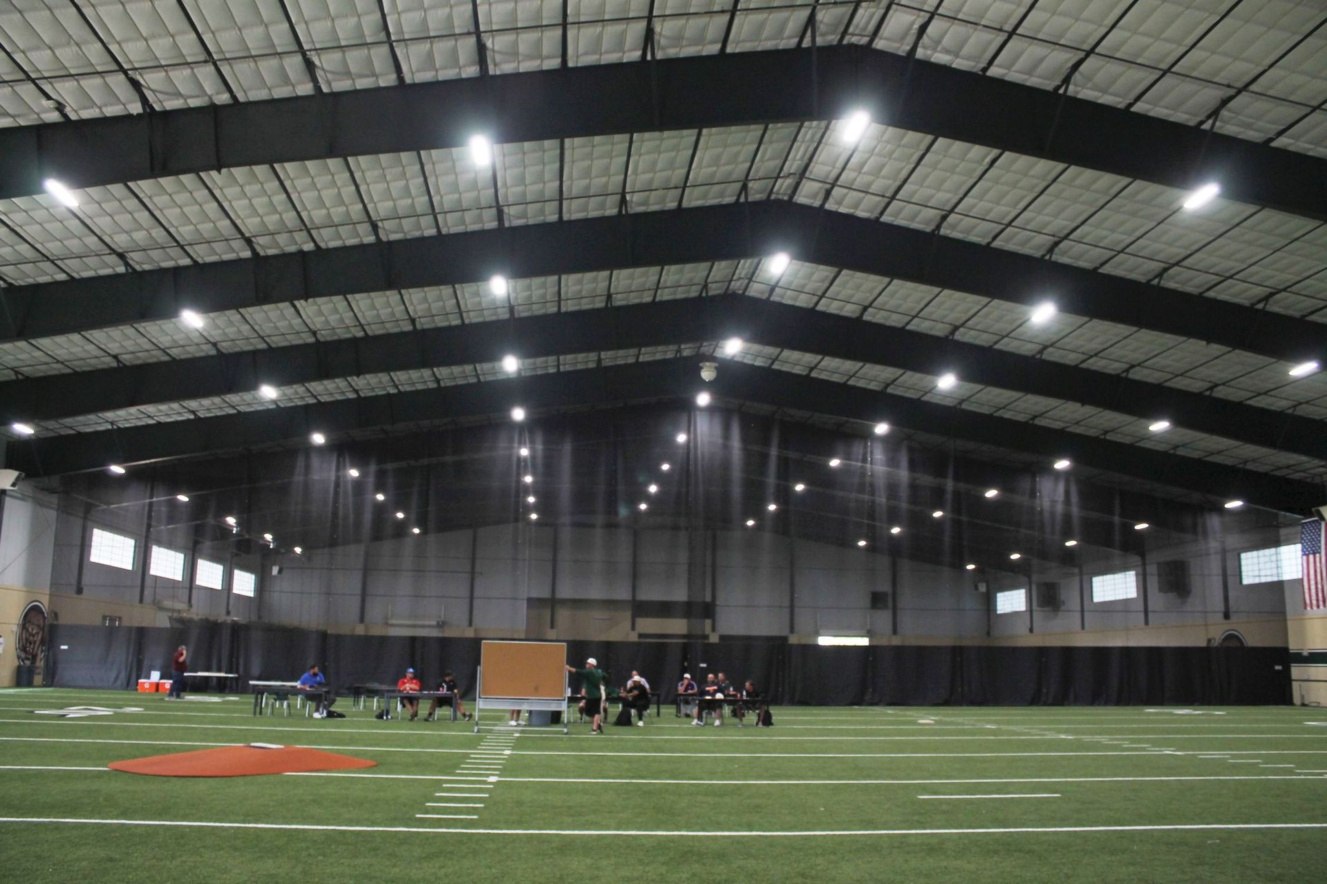 A large indoor football field with a lot of lights on it