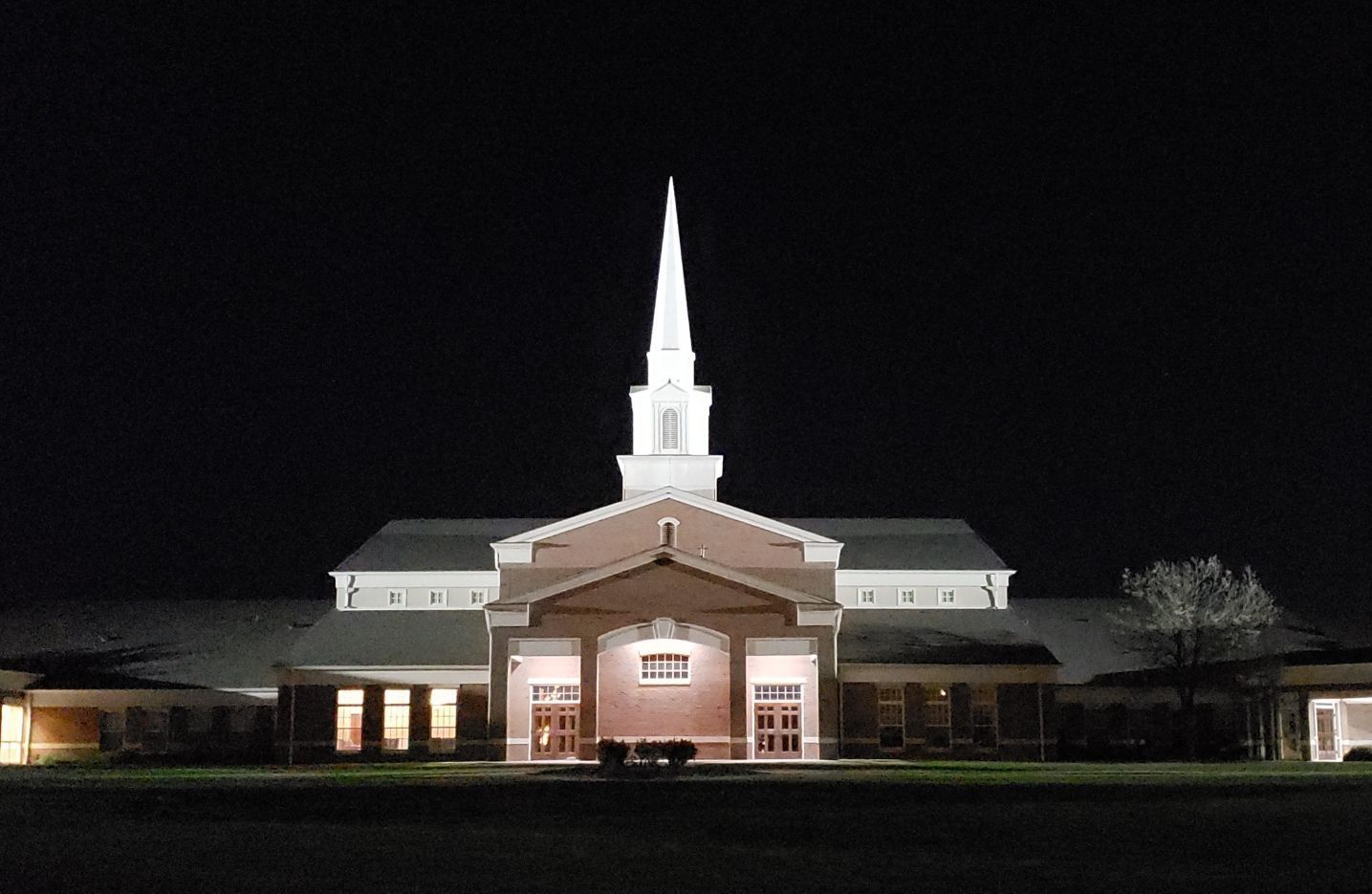 A church with a steeple lit up at night