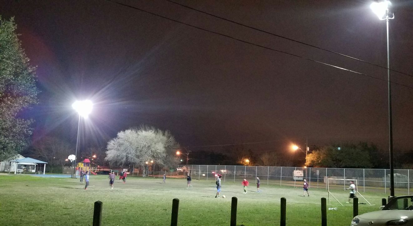 A group of people are playing soccer in a field at night.