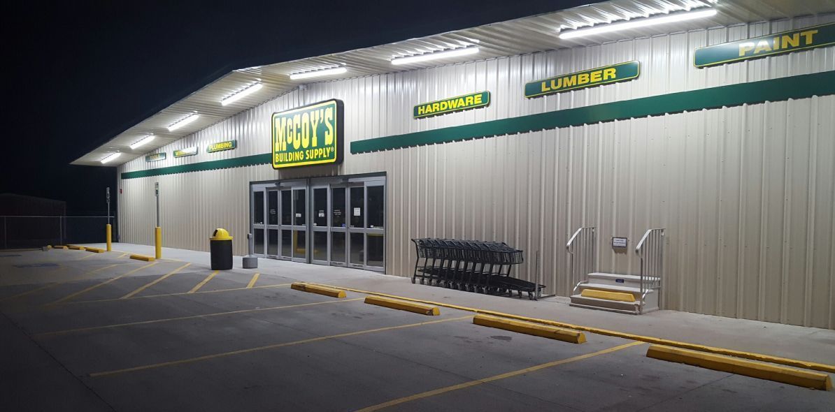 A store front with a parking lot in front of it at night.