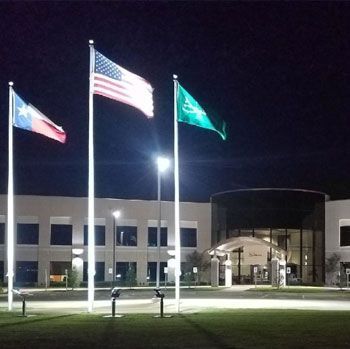 Three flags are flying in front of a building at night