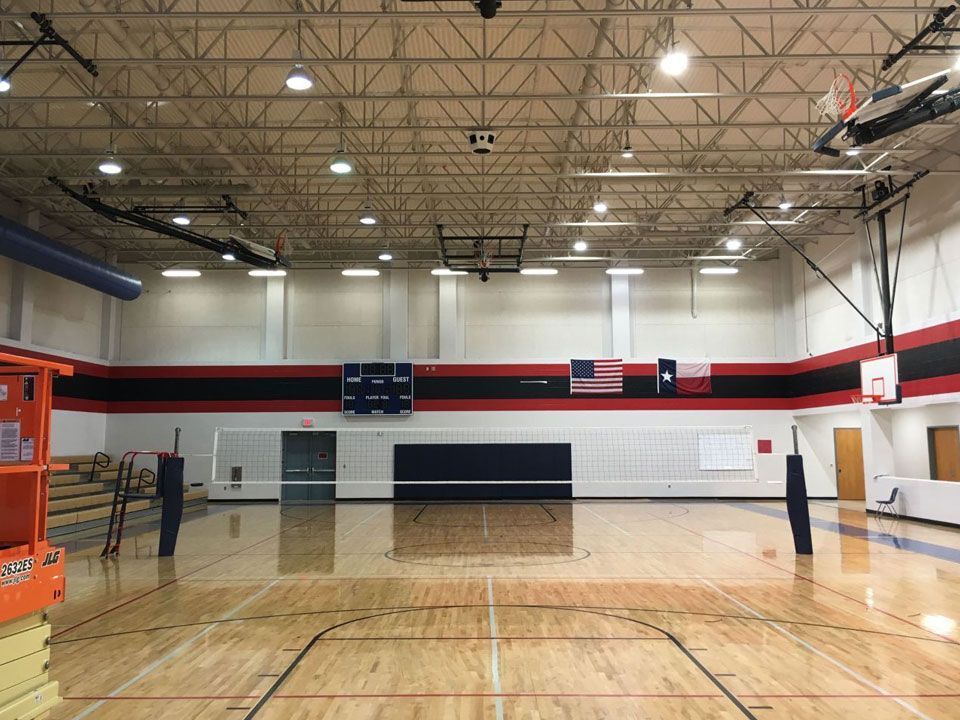 An empty gym with a volleyball court and a basketball court