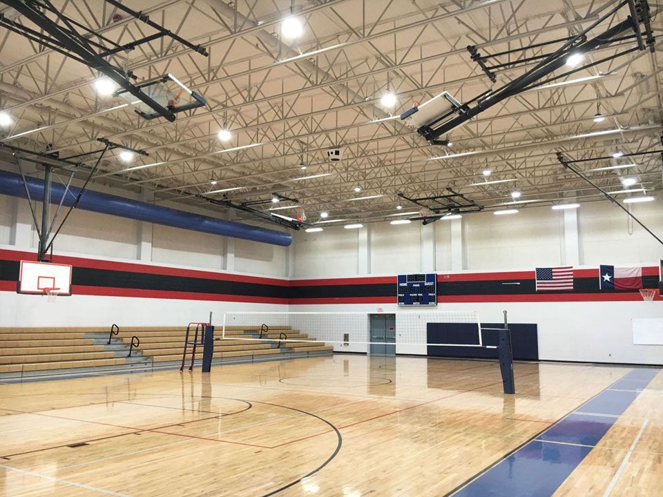 An empty gym with a basketball hoop and a volleyball net