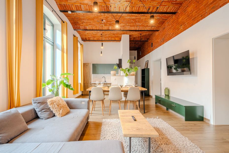 Bright modern living room with gray sofa, wood ceiling, dining table, and wall-mounted TV