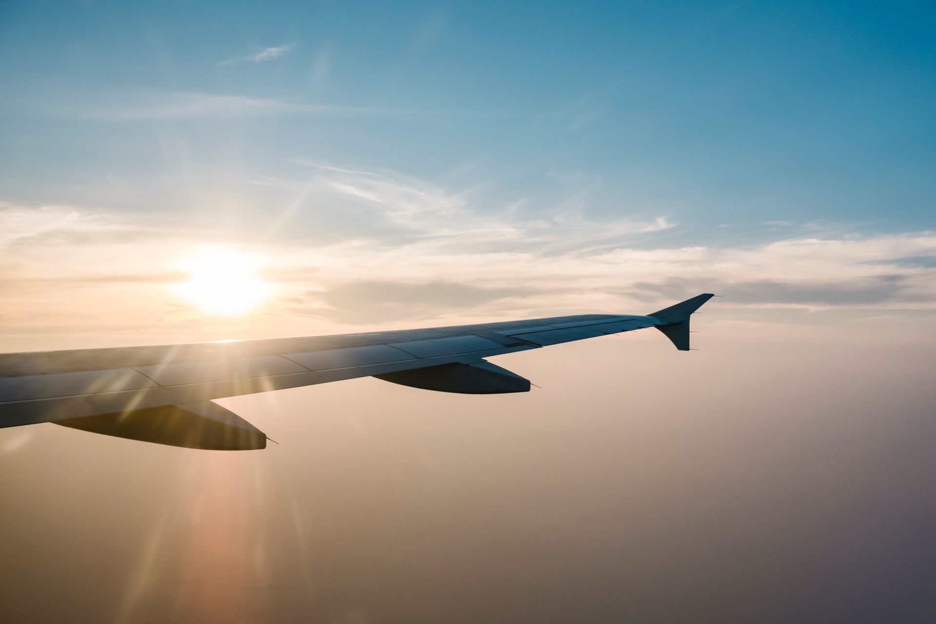 Der Flügel eines Flugzeugs fliegt bei Sonnenuntergang durch den Himmel.