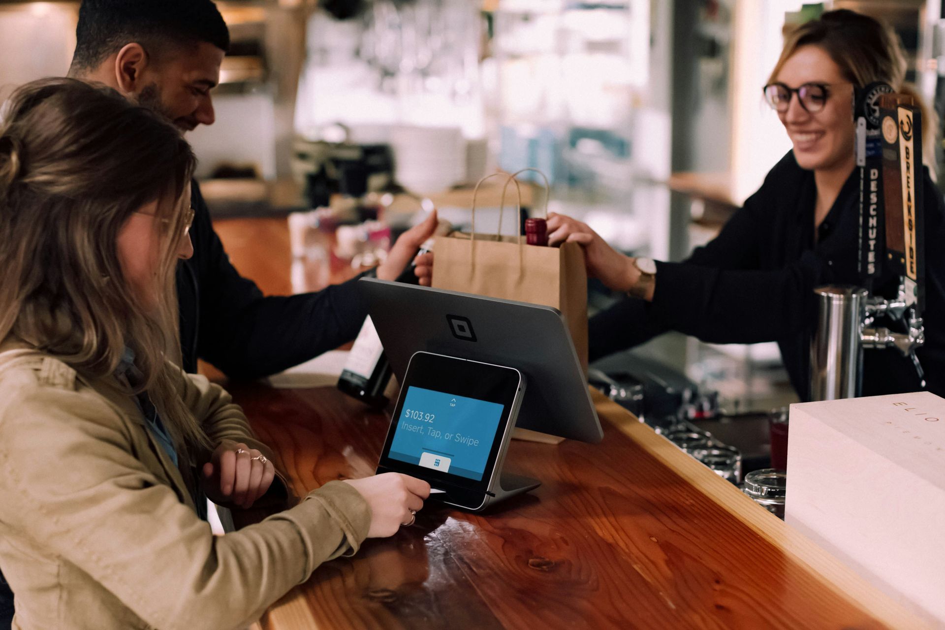 Ein Mann und eine Frau sitzen in einer Bar und nutzen ein Tablet.
