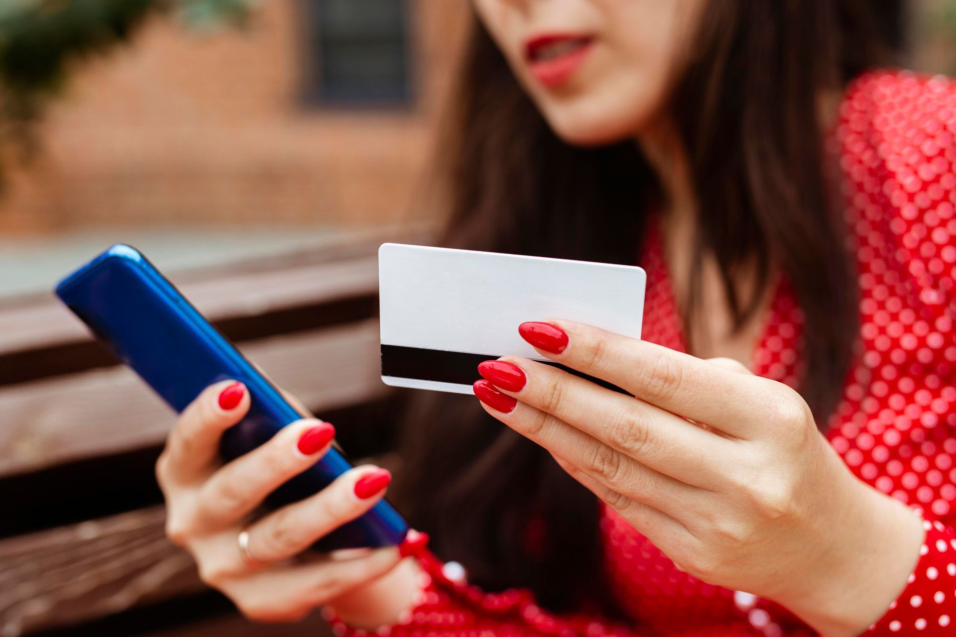 Eine Person die eine weiße Mastercard in der Hand hält und ein mobile App zu hält.