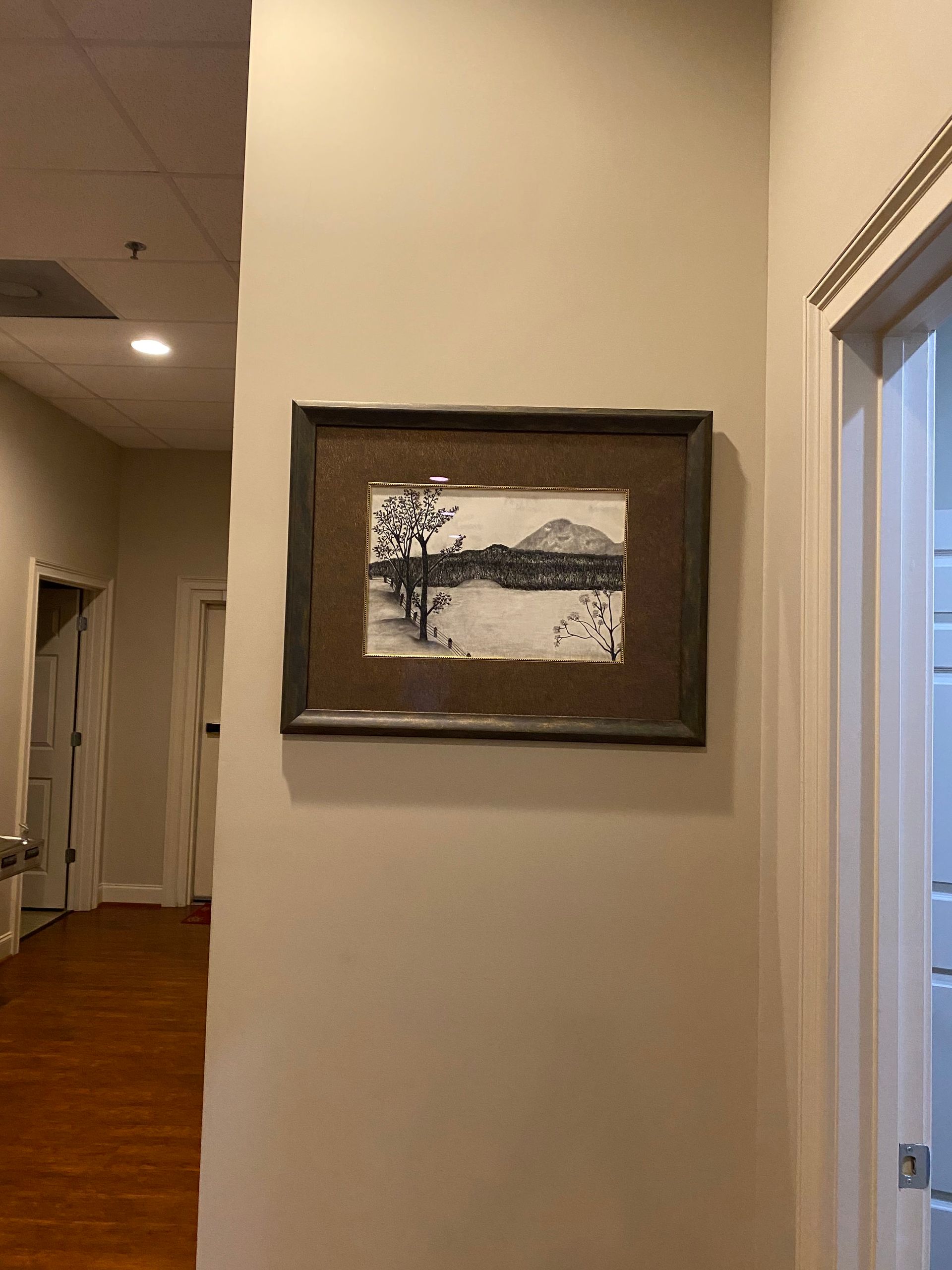 A black and white painting is hanging on a wall in a hallway.