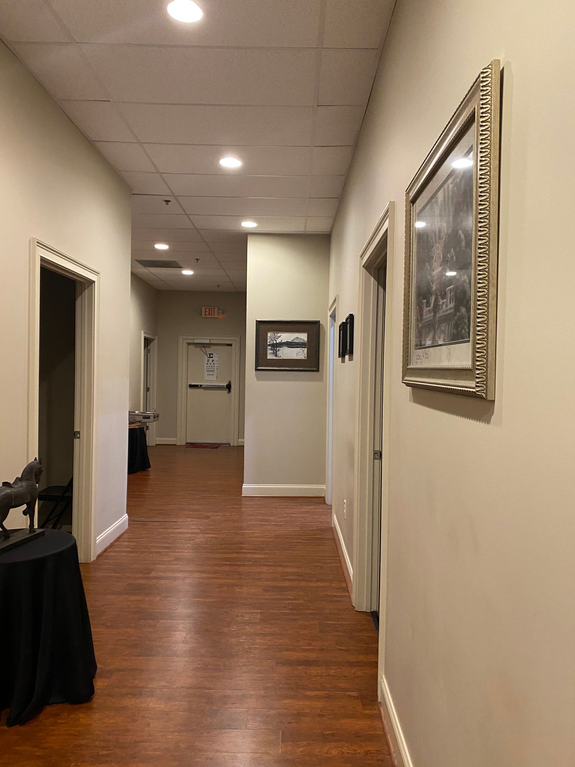 A long hallway with wooden floors and a picture on the wall