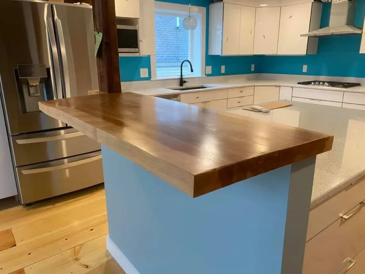 A kitchen with a wooden counter top and a stainless steel refrigerator.