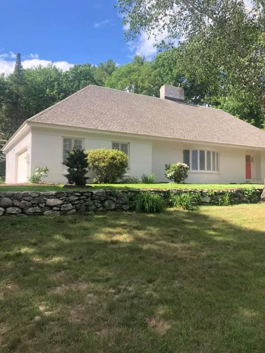 A white house with a stone wall in front of it