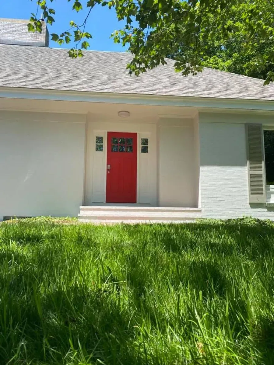 A white house with a red door and a gray roof