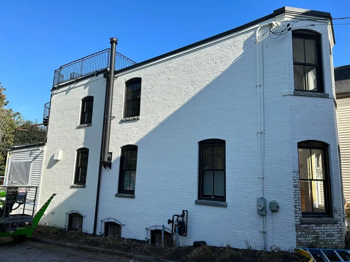 A white building with black windows and a balcony on top of it.