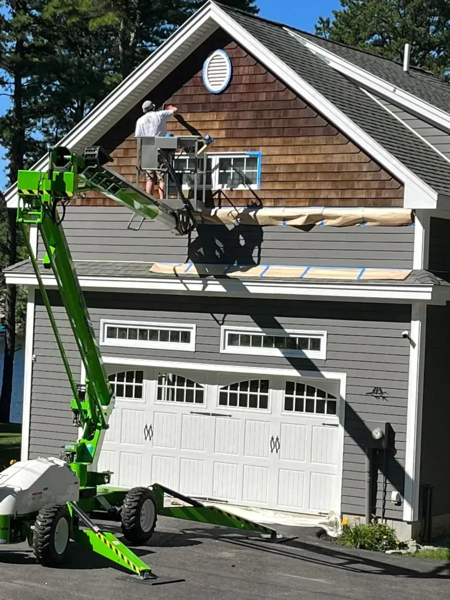 A green crane is working on the roof of a house