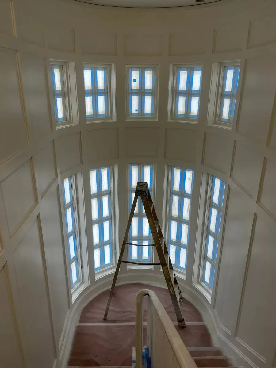 A ladder is in the middle of a staircase with lots of windows