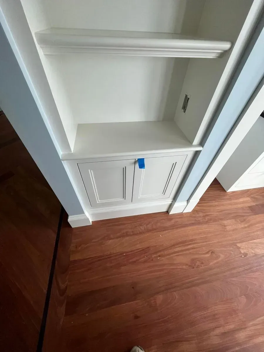 A closet with a door and shelves in a room with hardwood floors.