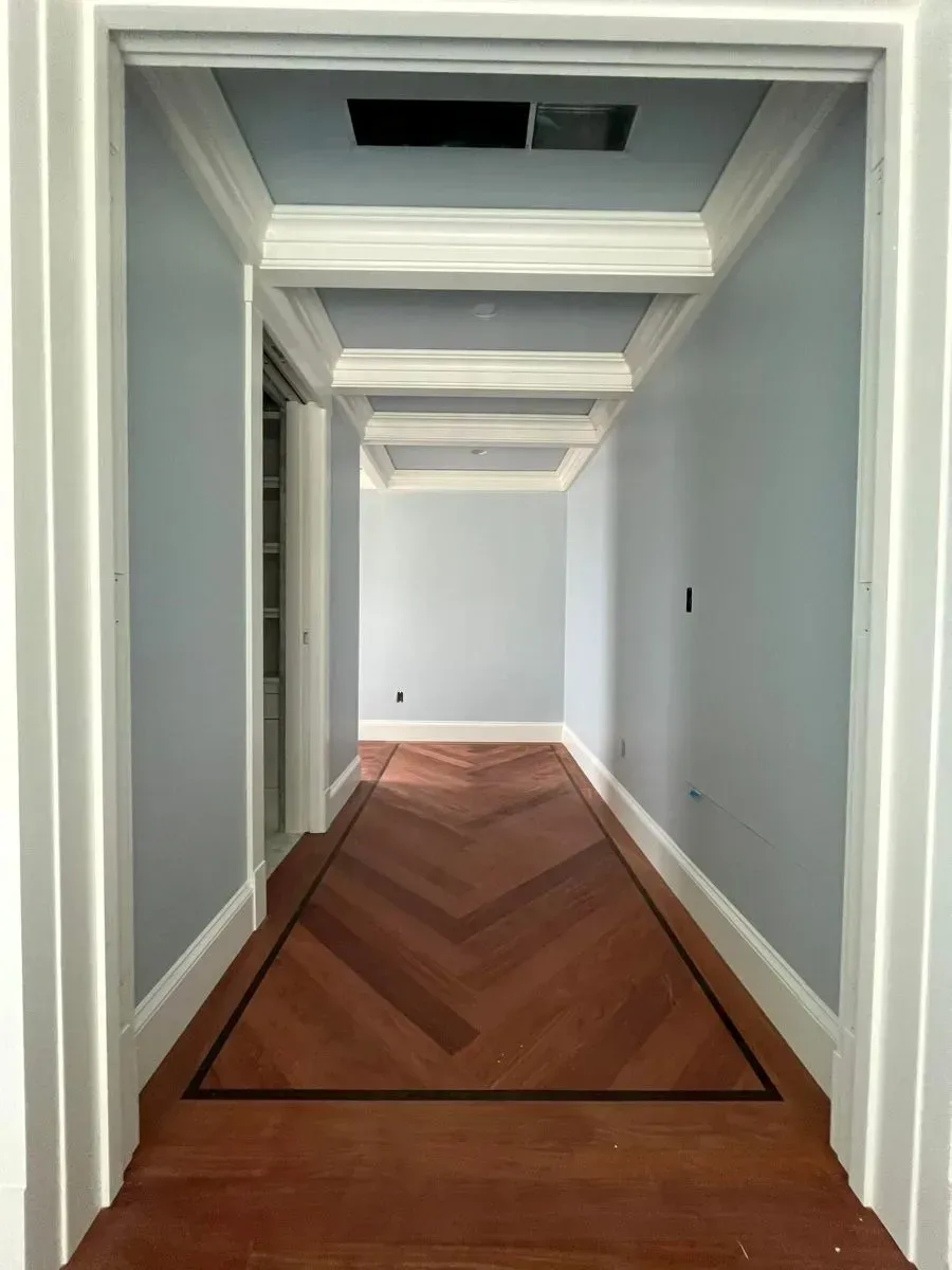 A hallway with a wooden floor and white trim
