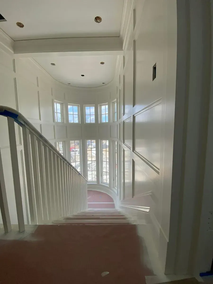 A staircase in a house with white walls and a pink carpet.