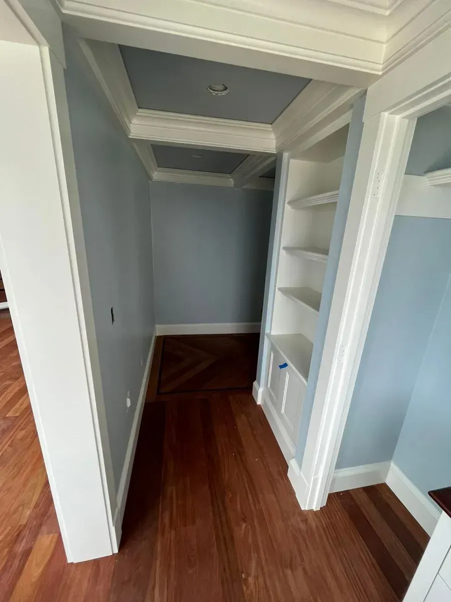 A hallway with hardwood floors and shelves in a house