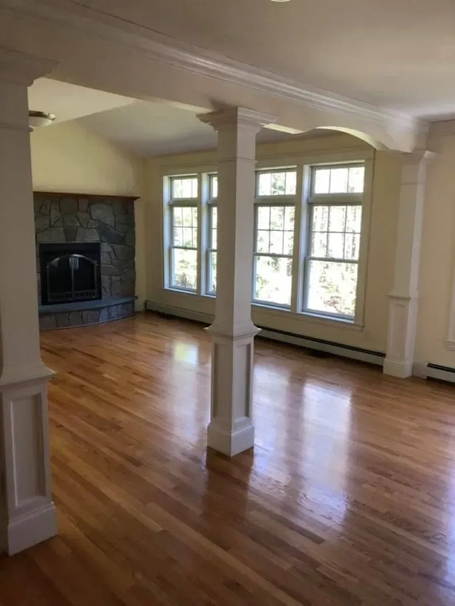 An empty living room with hardwood floors and a fireplace.
