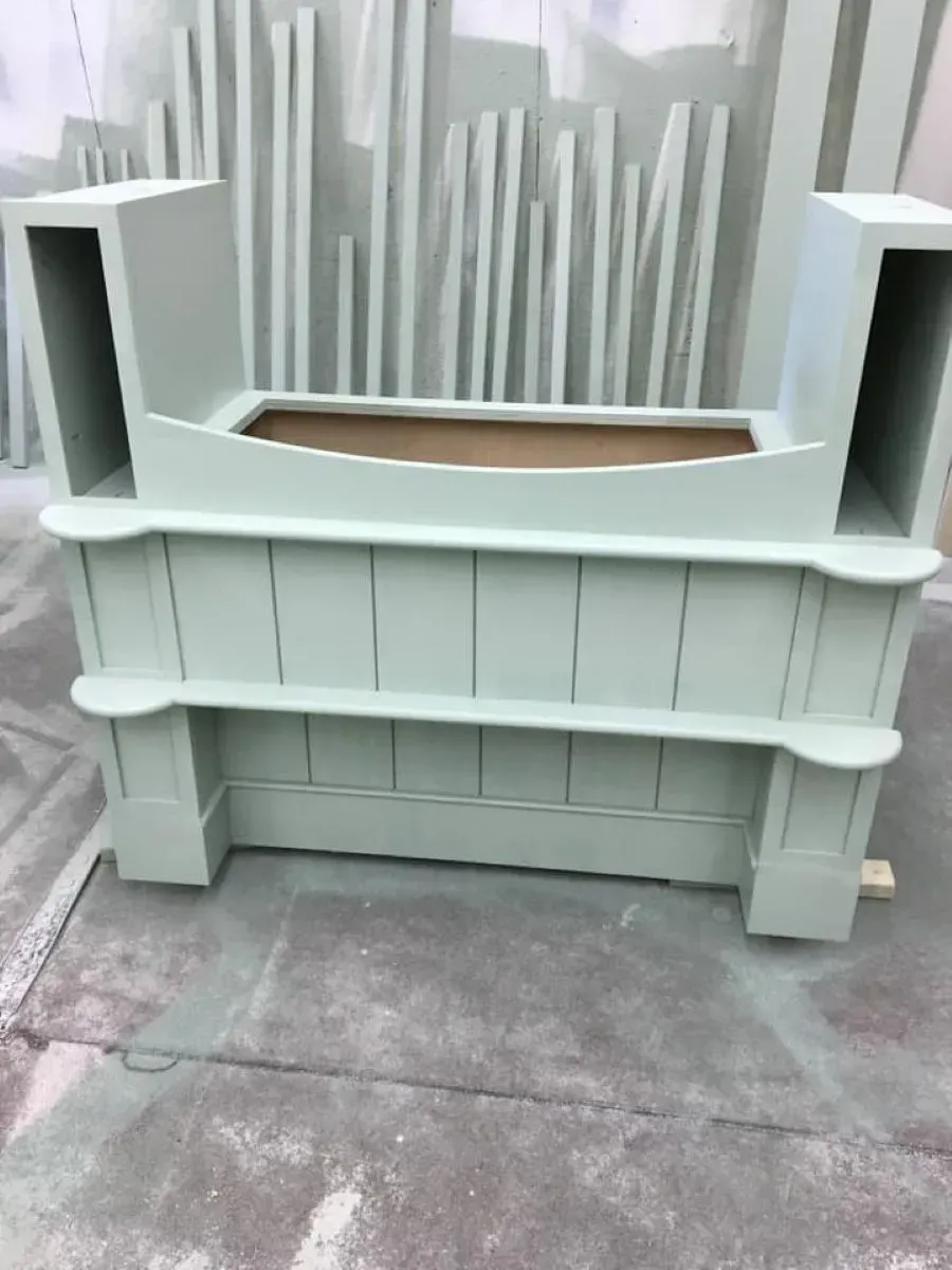 A wooden bench with a planter in the middle is sitting on the ground.