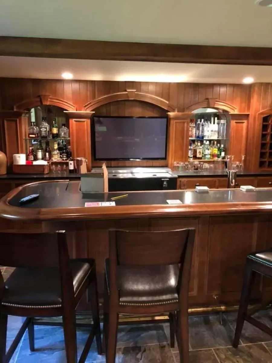 A bar with stools and a flat screen tv on the wall.