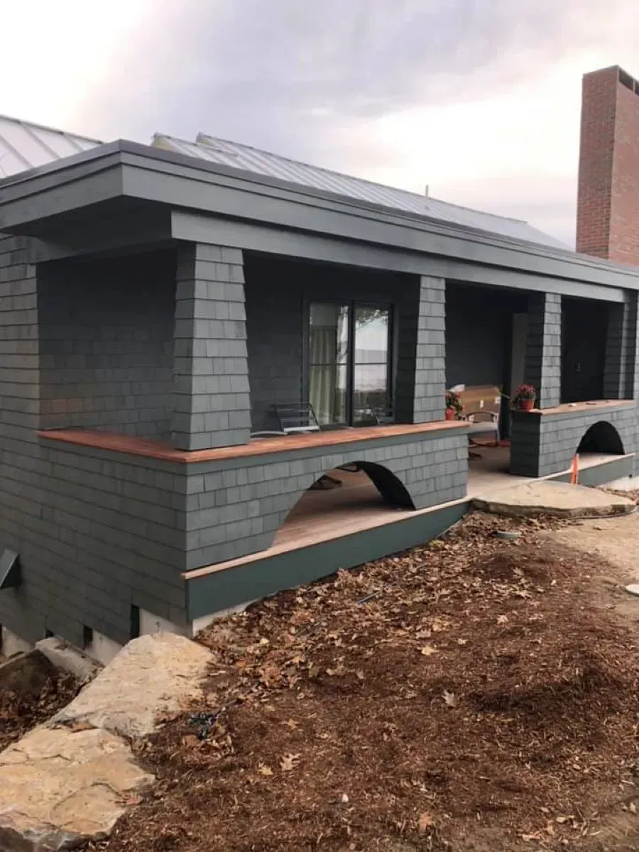 A brick house with a porch and a chimney is being built.