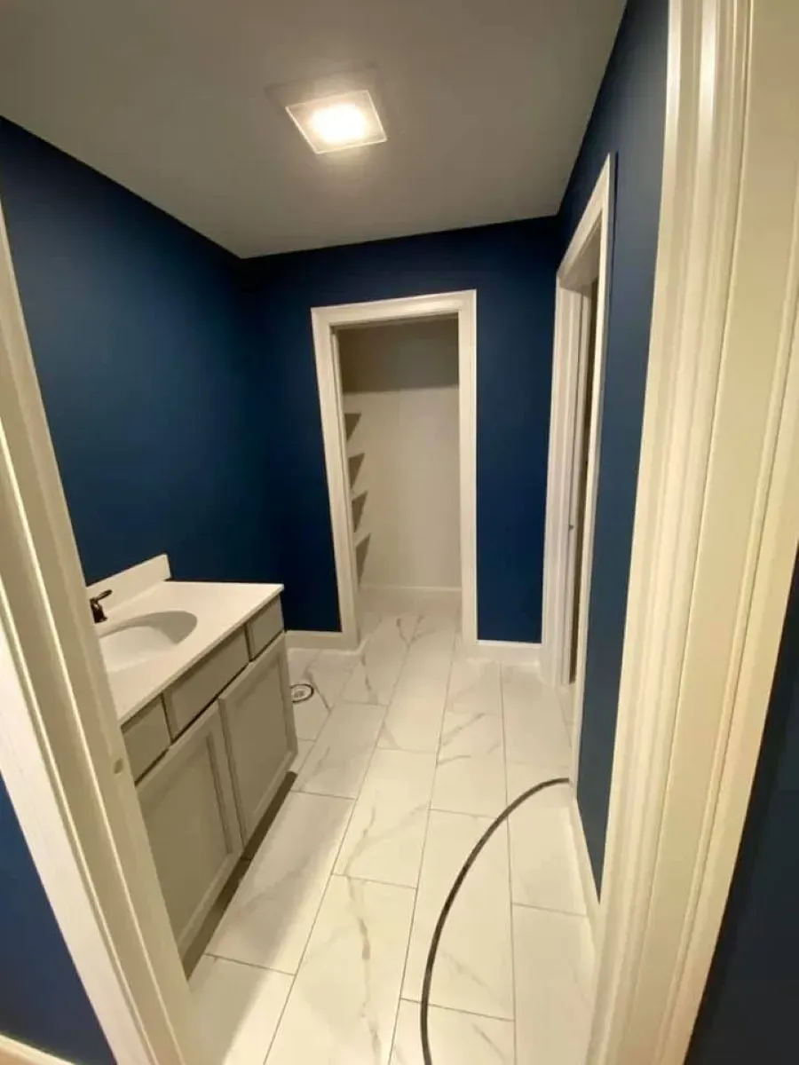 A bathroom with blue walls , a sink , and a closet.