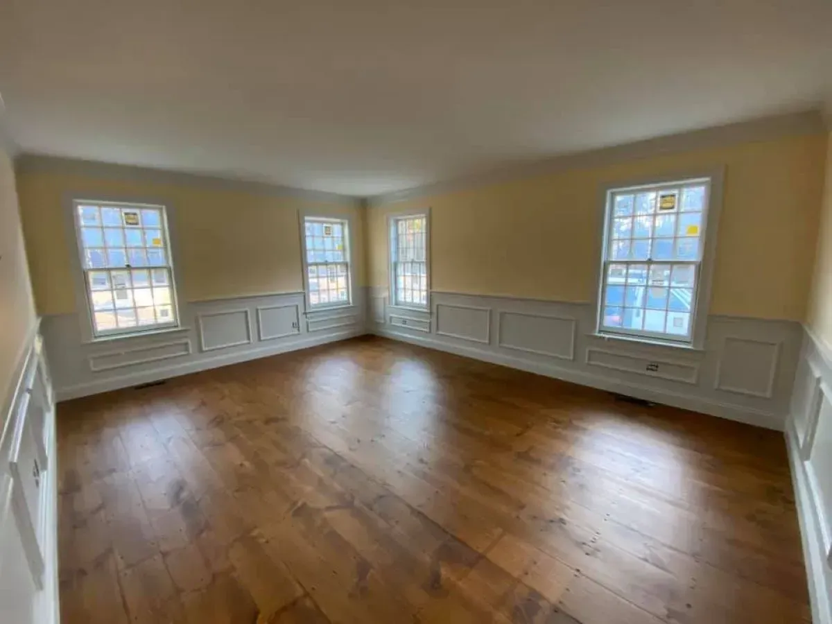 An empty living room with hardwood floors and yellow walls.