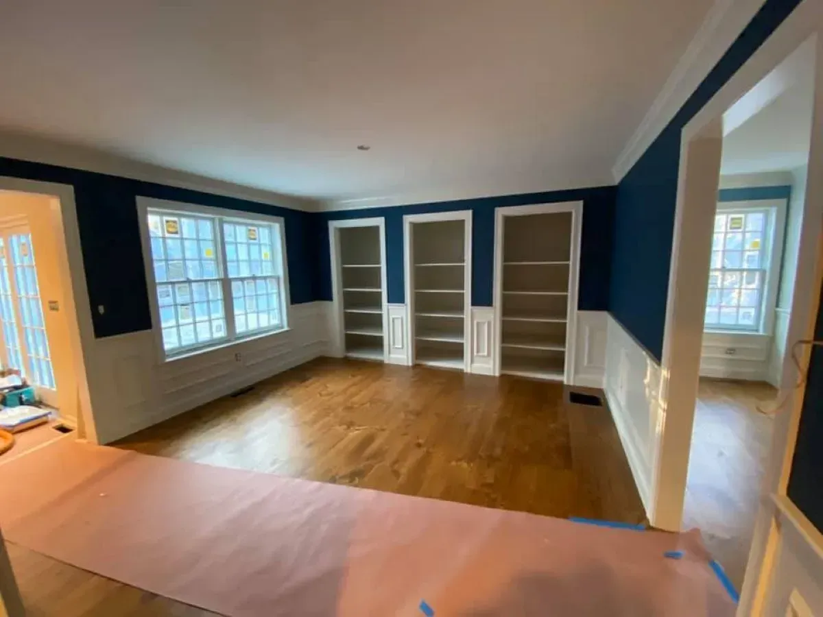 An empty room with blue walls and white shelves