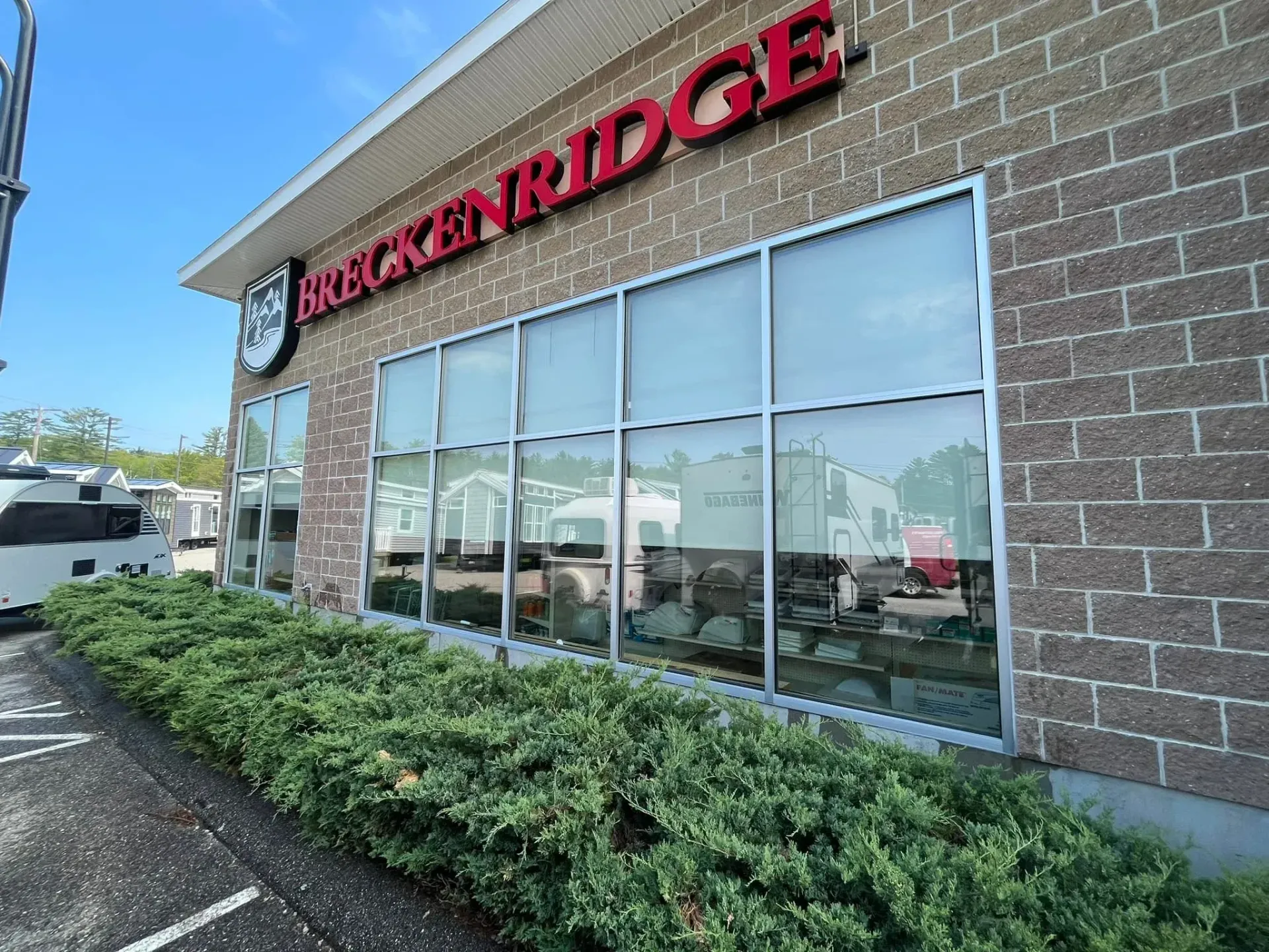 A large brick building with a lot of windows and bushes in front of it.