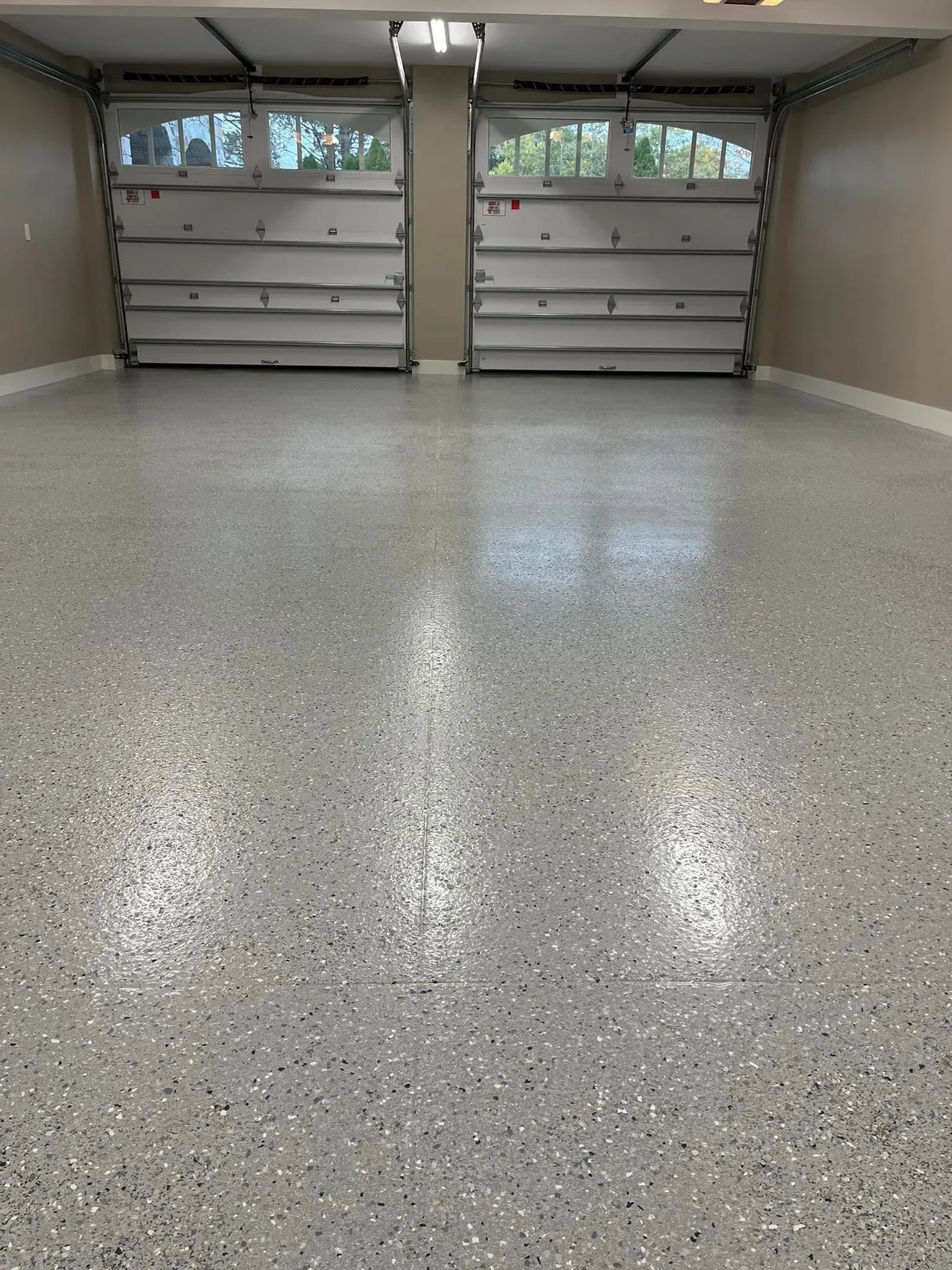 A garage with two garage doors and a shiny floor.